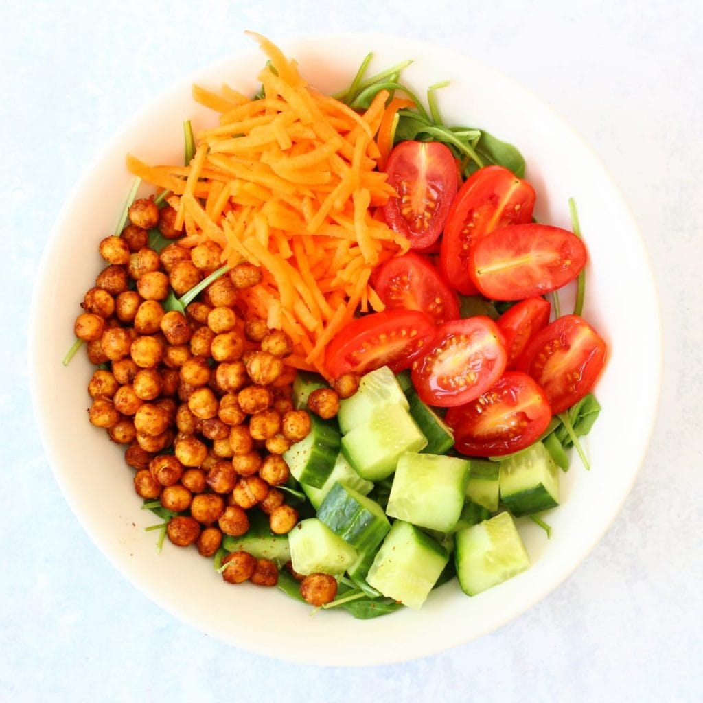 Bowl of roast chickpea salad with cucumber, tomatoes, carrot and rocket as well as roasted chickpeas