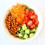 Bowl of roast chickpea salad with cucumber, tomatoes, carrot and rocket as well as roasted chickpeas