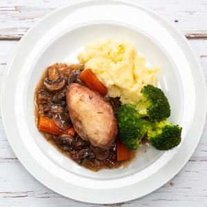 Plate of coq au vin with mashed potatoes and broccoli