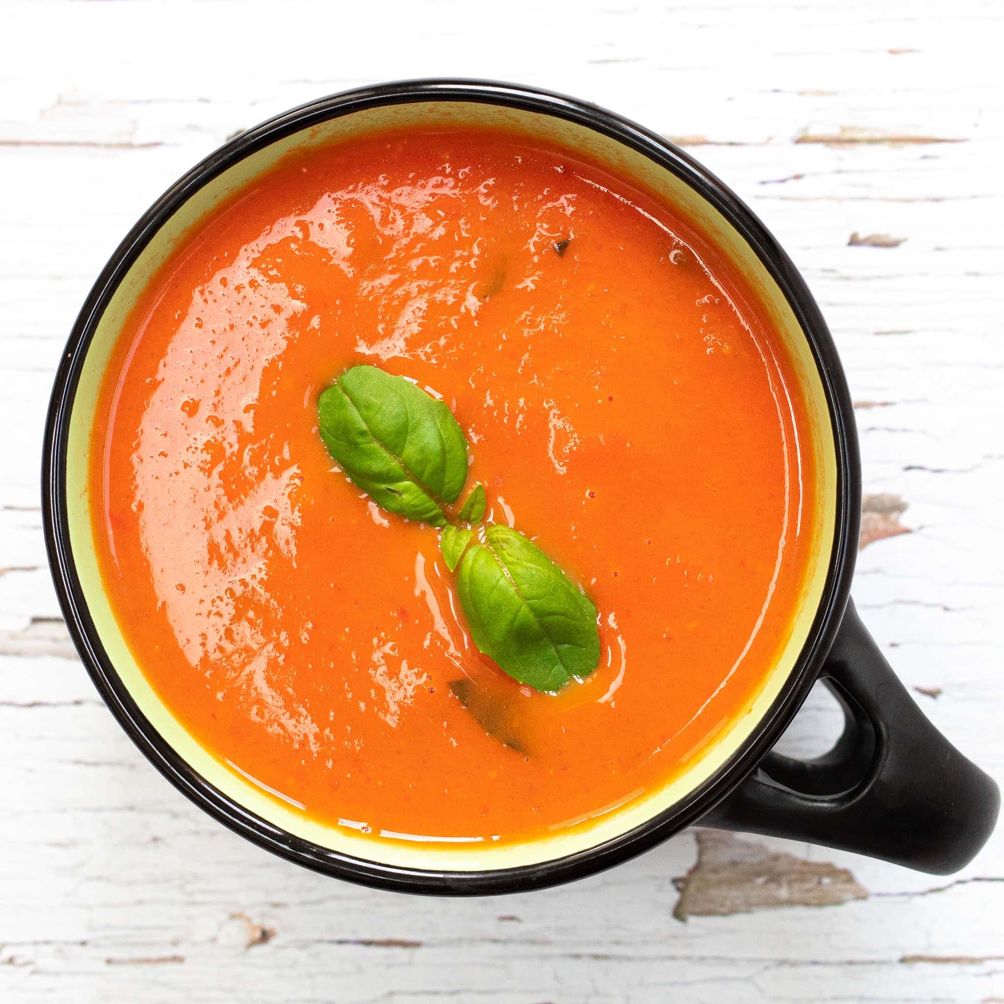 classic tomato soup in a bowl with basil on top
