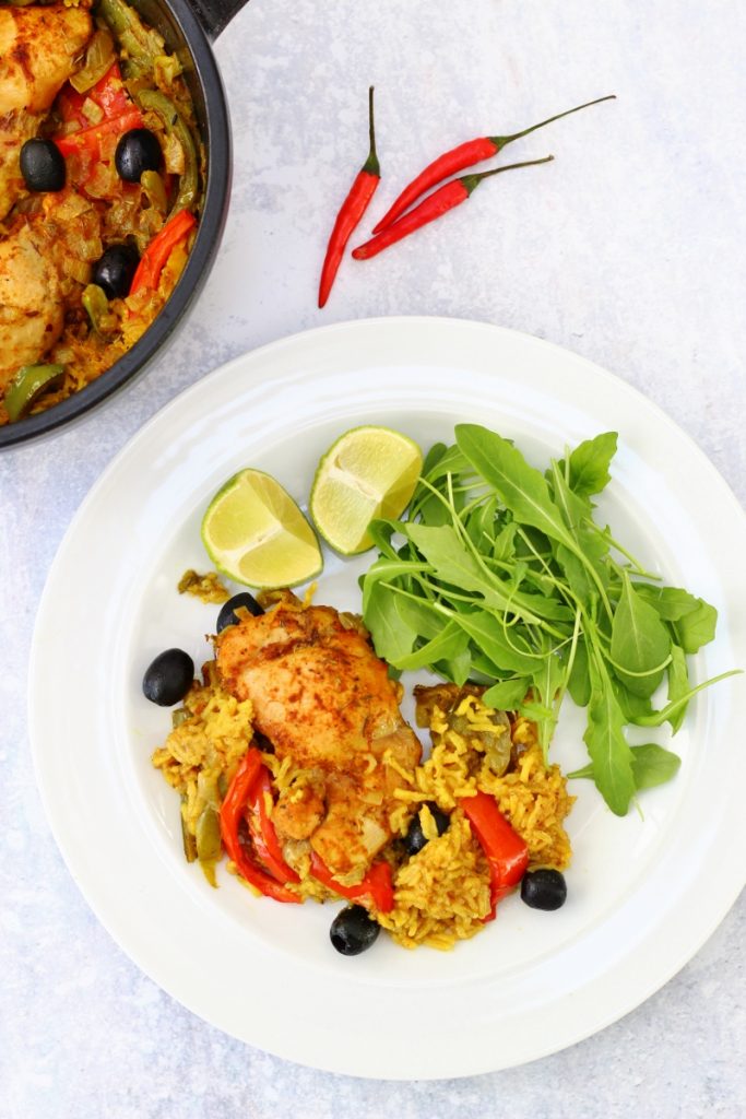 Pot and plate of Puerto rican chicken dish which is chicken cooked in spicy rice