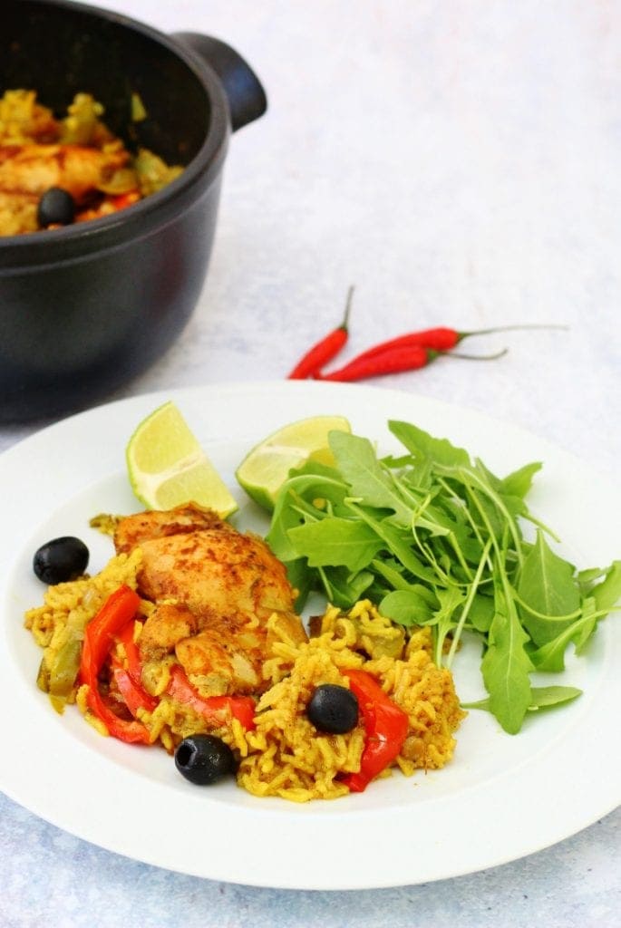 Plate of puerto rican chicken and pan with a couple of chilli peppers