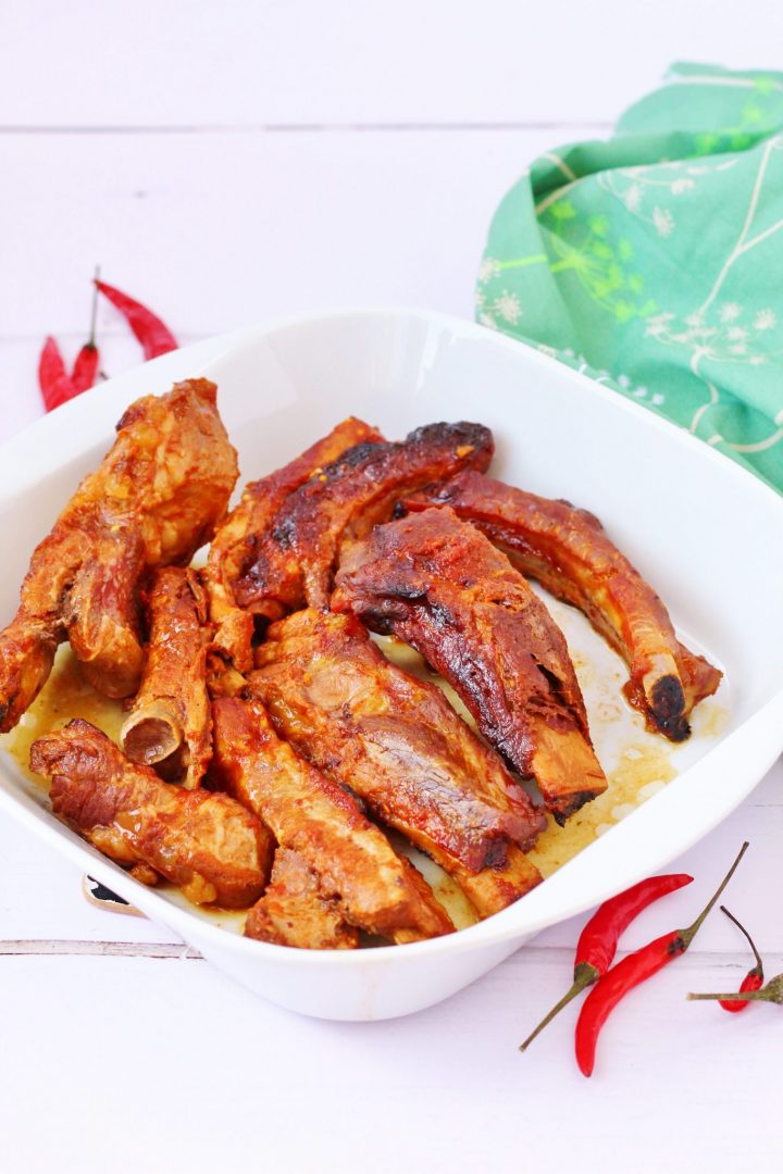 Slow cooked barbecue ribs in a white bowl with some red chillies on the side