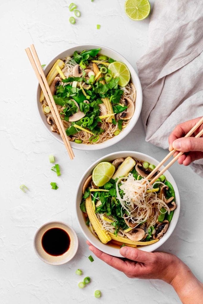 two bowls of instant noodle soup with hands