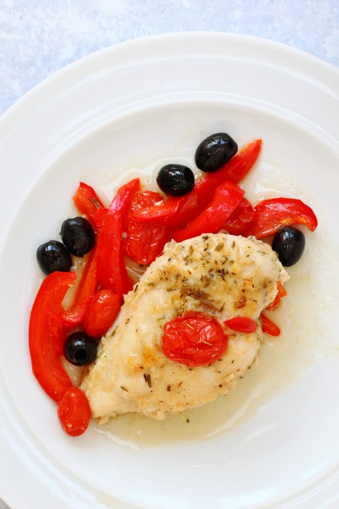 Baked Italian chicken iwth peppers, tomotoes and olives on a plate