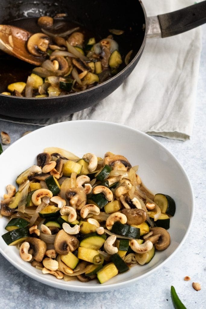 Courgette and mushroom stir fry in a bowl and a wok