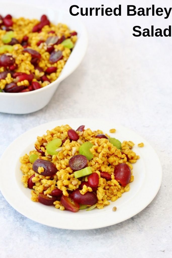 Curried pearl barley salad on a plate with a serving bowl in the background