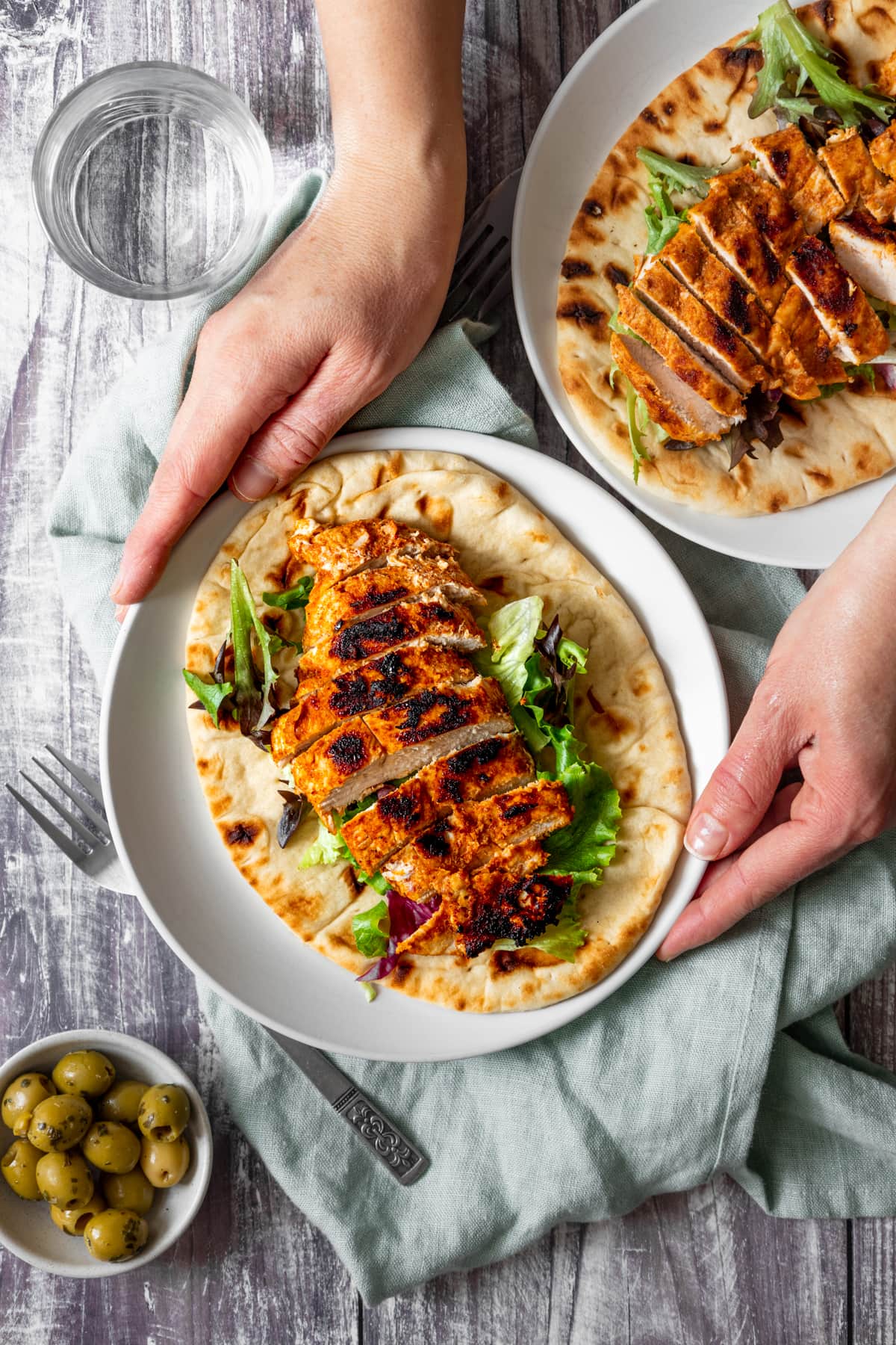 Hands holding plate of marinated griddled chicken