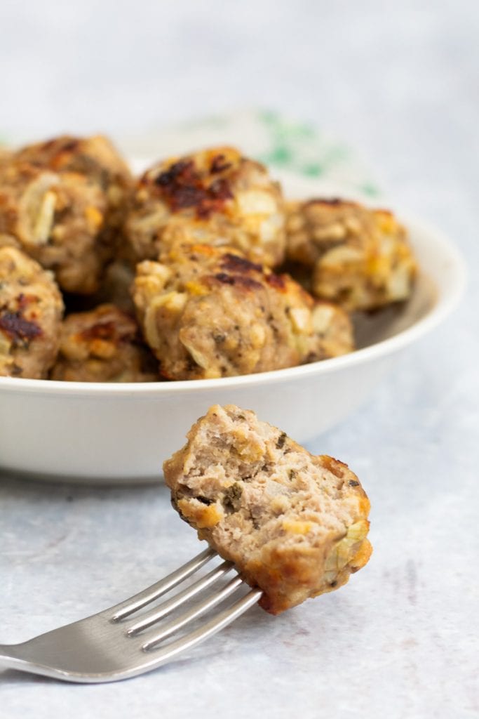 Sage onion stuffing balls in a bowl with one on a fork