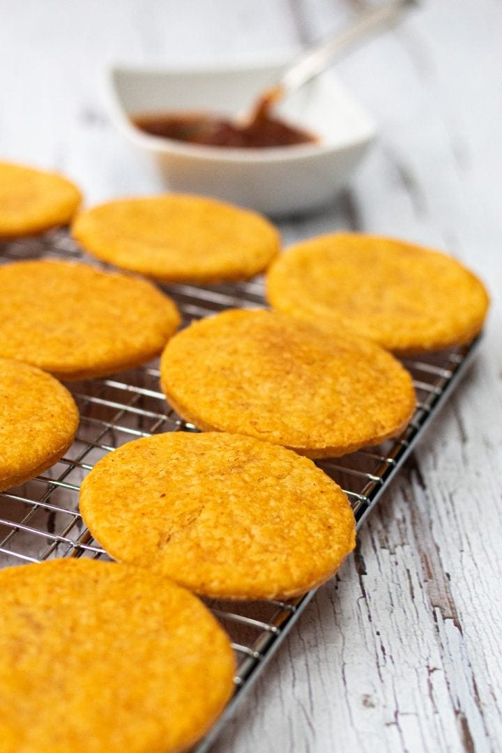 Homemade savoury cheese crackers on a cooling rack with a chili jam on the side