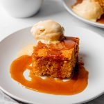 Sticky toffee pudding on a plate topped with sauce and ice cream