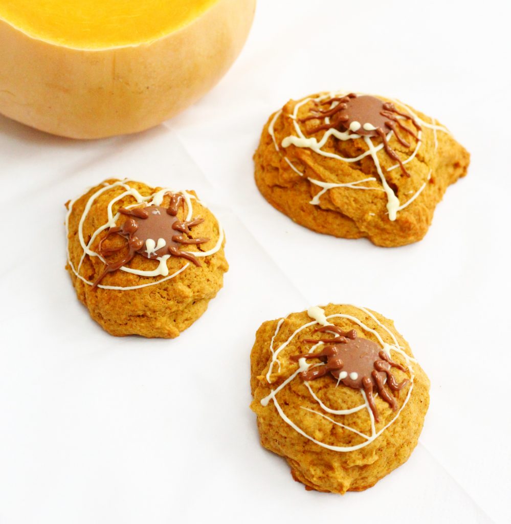 Spiced pumpkin cookies decorated with chocolate webs and spiders for Halloween