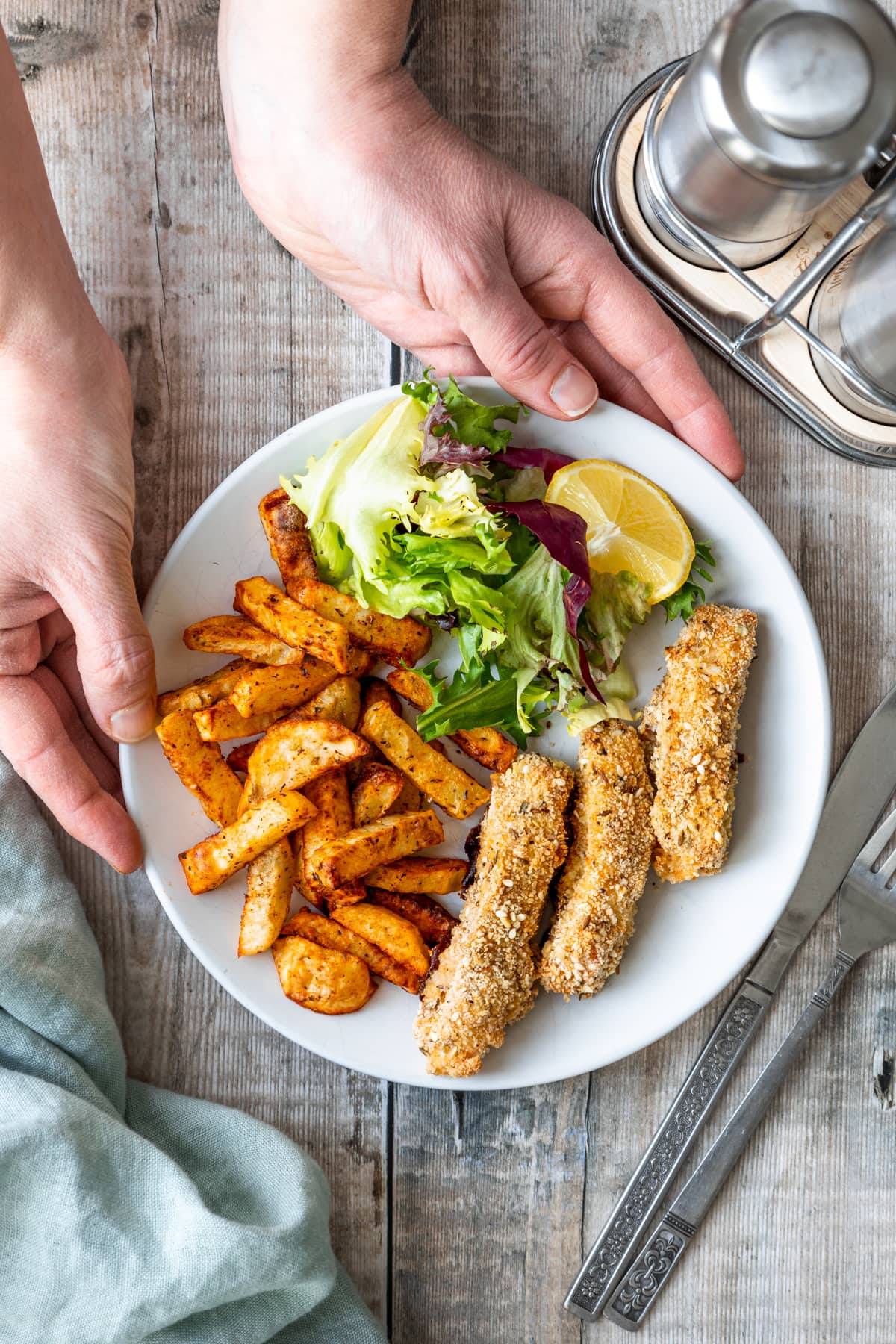 hands holding plate of homemade fish fingers and chips