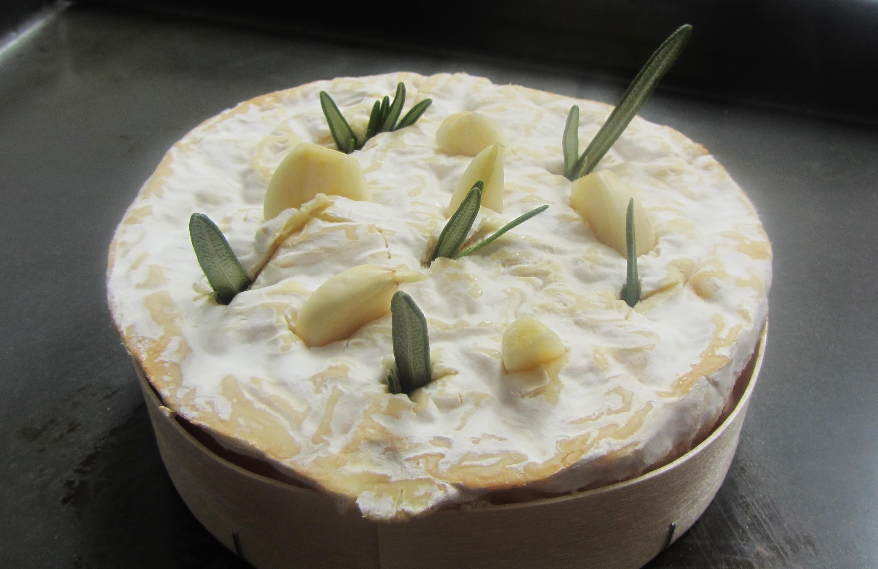 Tunworth cheese studded with garlic and rosemary, ready for baking