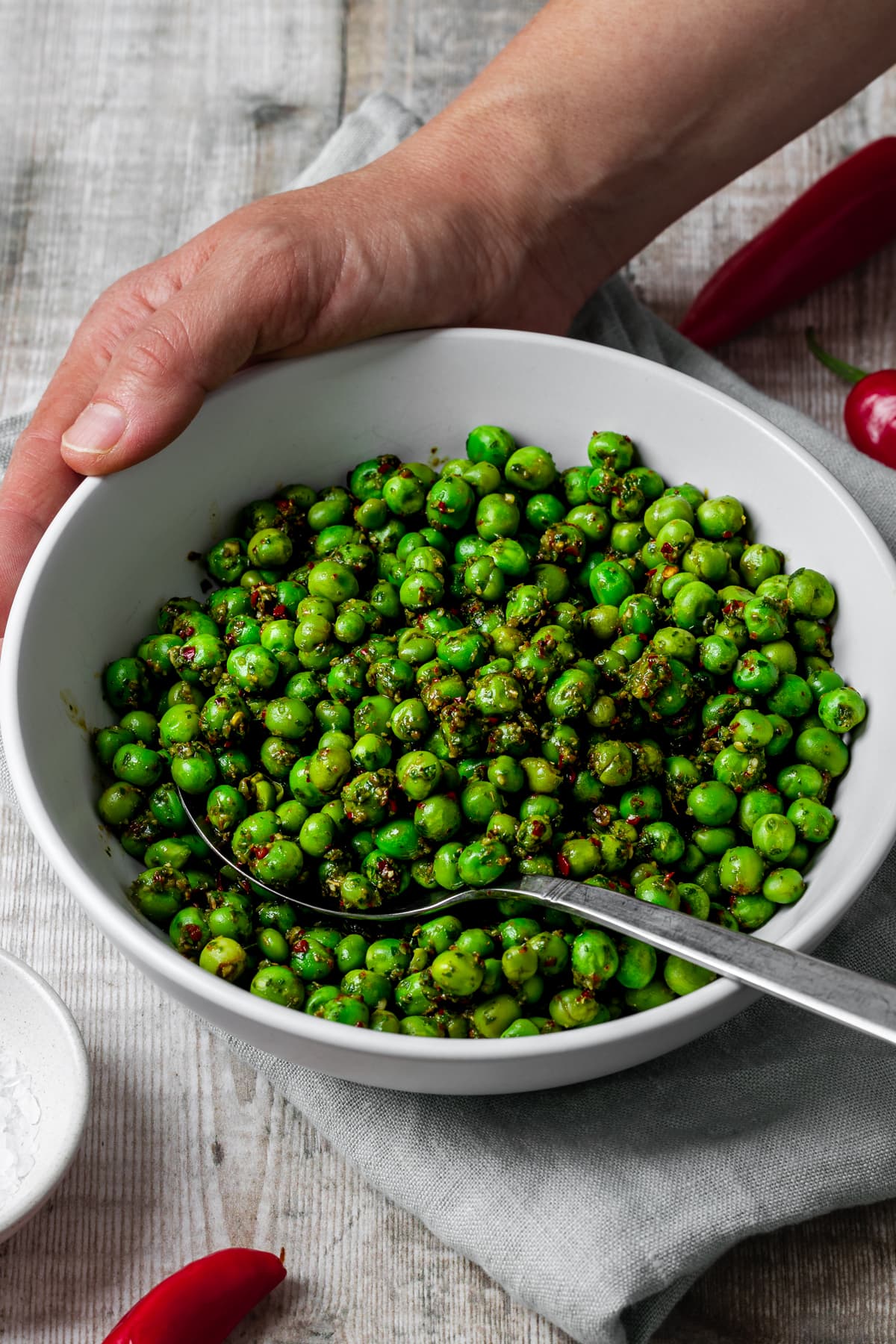 Hand holding bowl of chimichurri peas