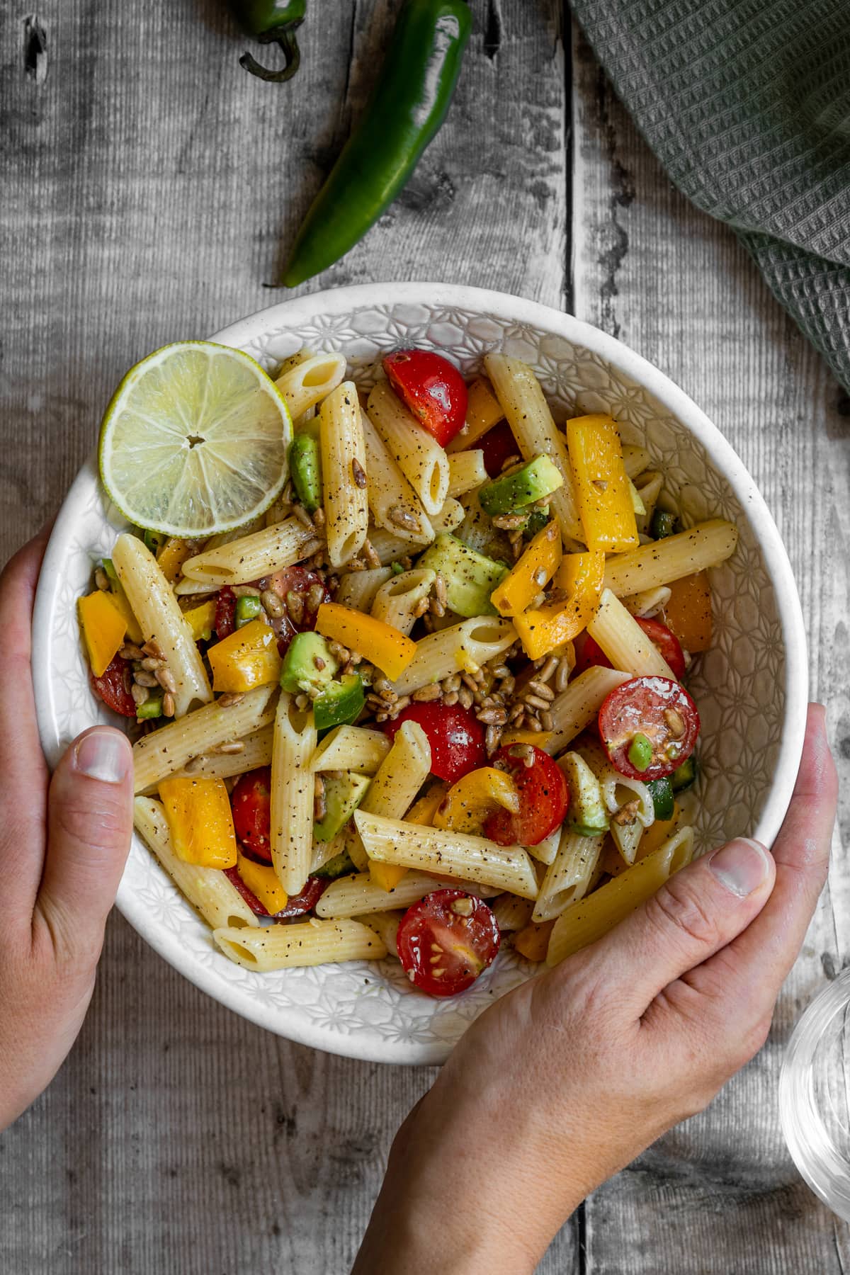 hands holding bowl of pasta salad