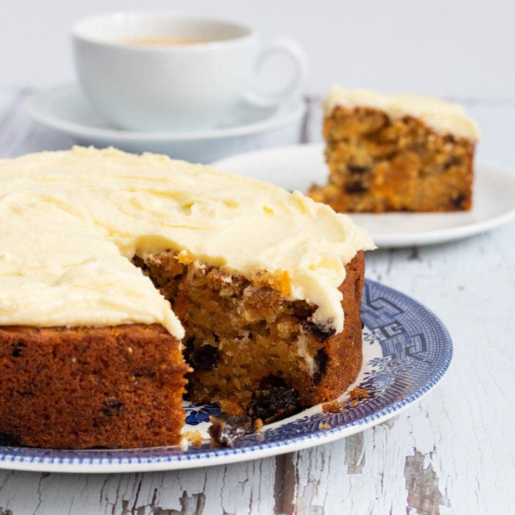 Carrot cake with a slice in the background and cup of coffee
