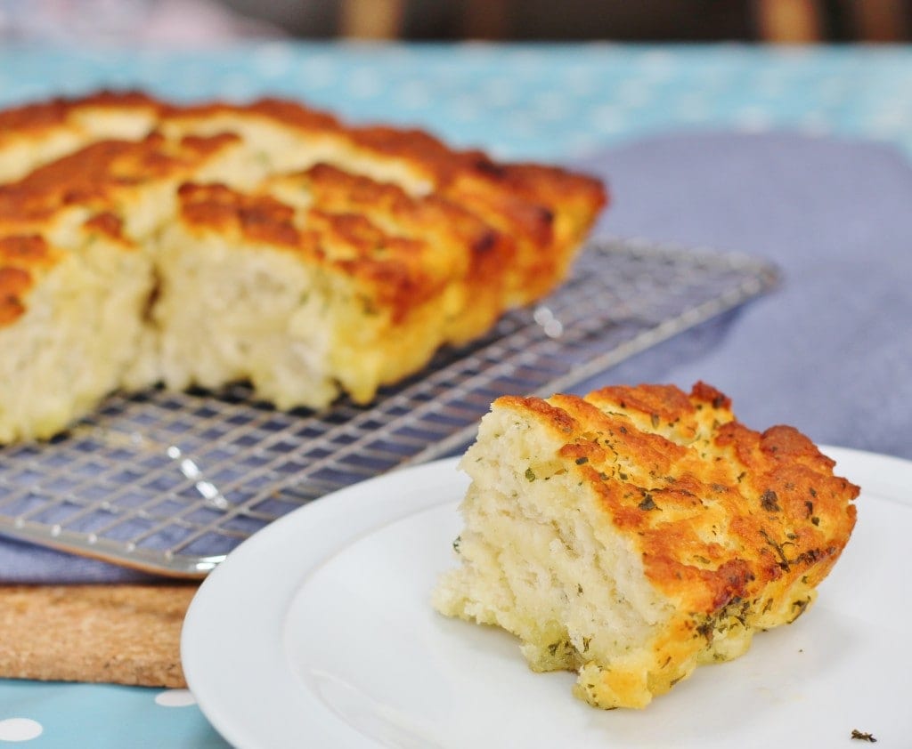 Garlic and Herb Butter Quick Bread on a cooling rack with bread on a plate