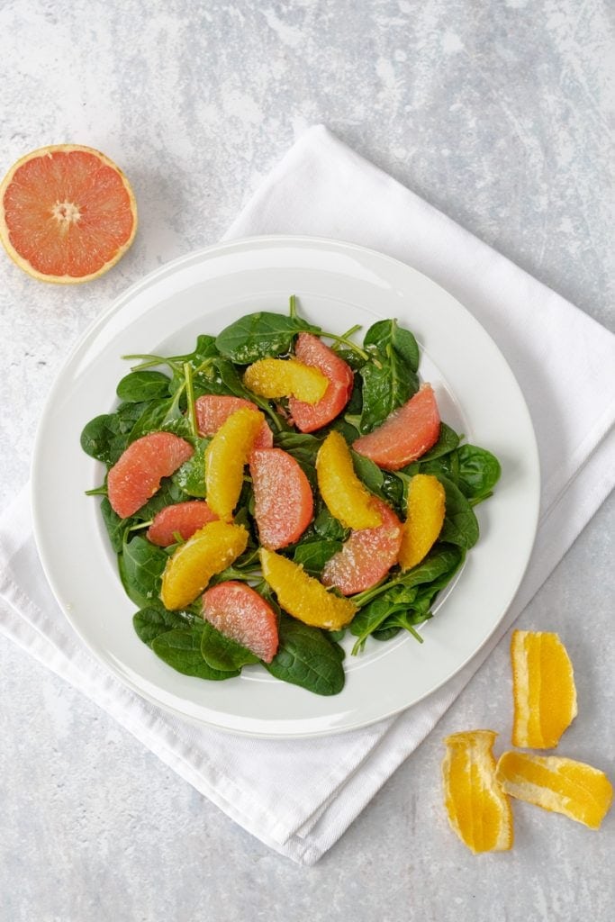 Plate of salad with spinach leaves and citrus fruit