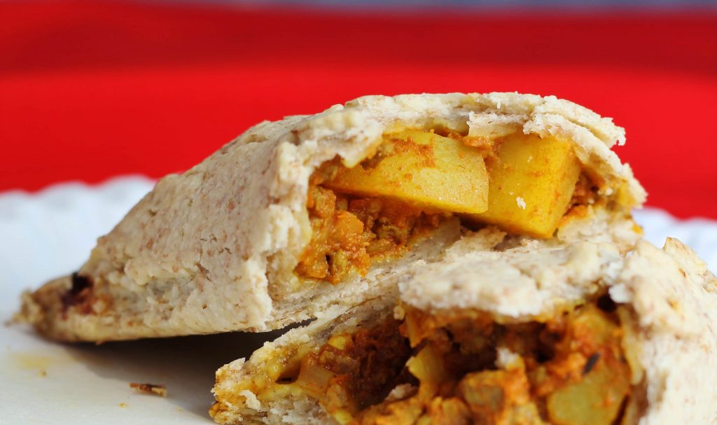 caribbean patties broken in half so you can see the filling