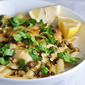 Chicken Piccata in a bowl with lemon wedges