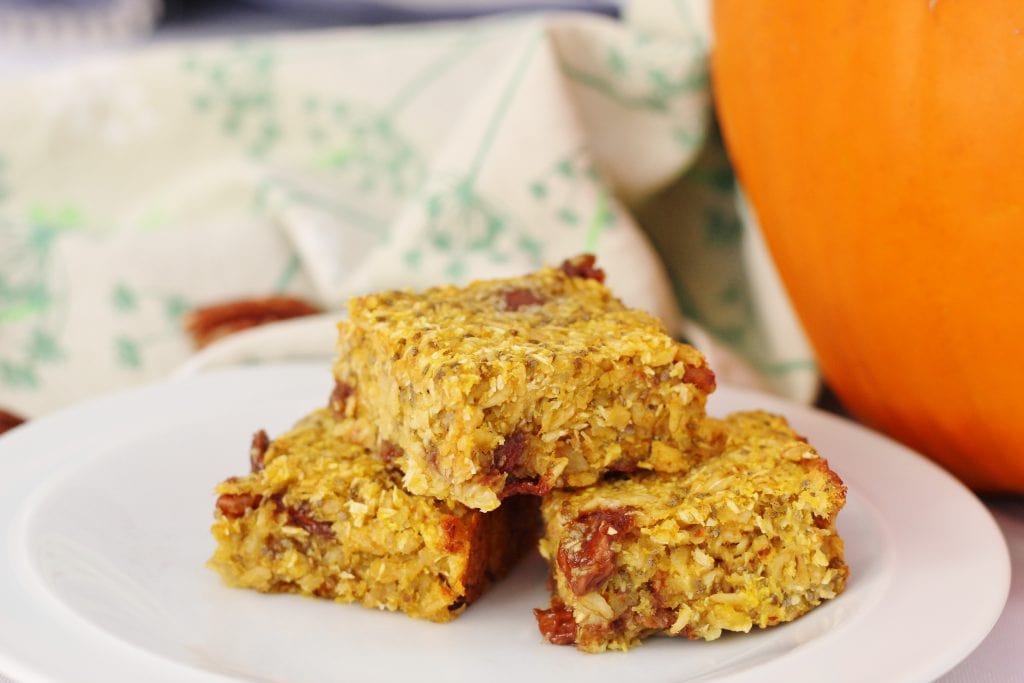 Pumpkin cereal bars with a pumpkin in the background