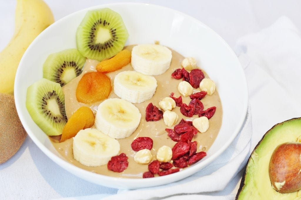 Nutella smoothie bowl topped with fresh and dried fruit and nuts.