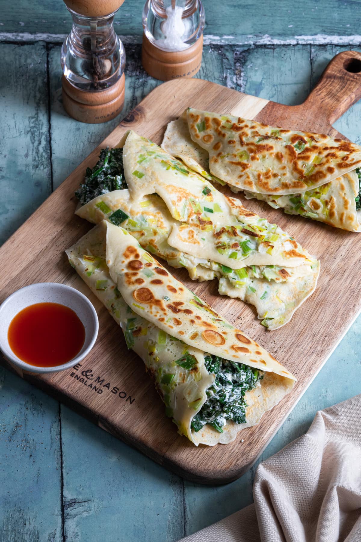 wooden board with rolled up leek crepes on