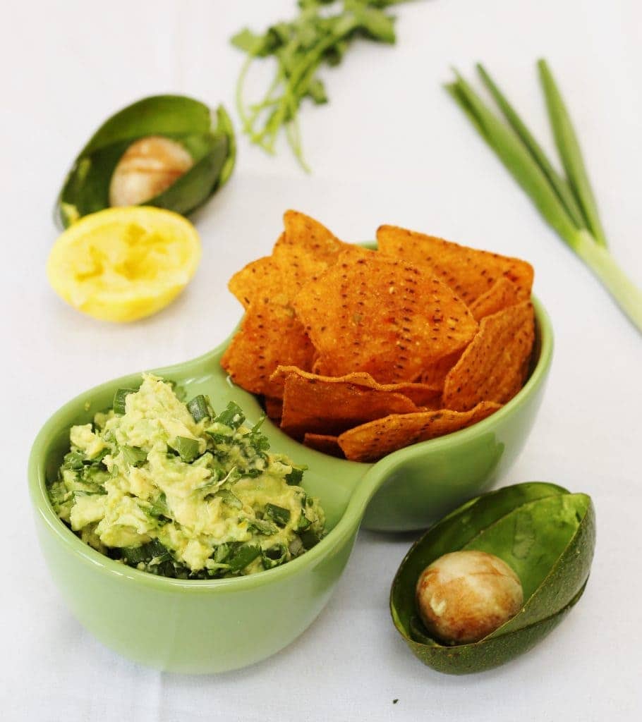 lemon and herb guacamole in a green bowl with tortilla chips