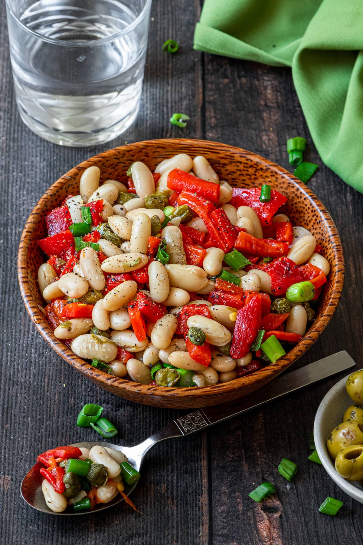 spanish bean salad in a bowl plus water and  spoon