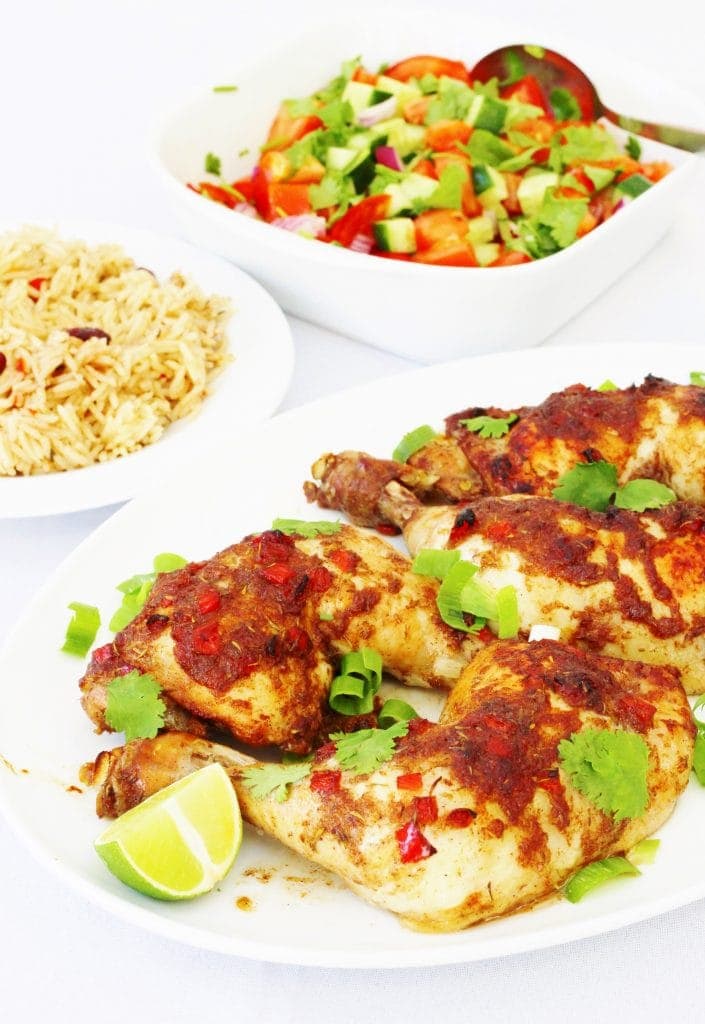 Plate of jerk chicken, bowl of rice and bowl of salad