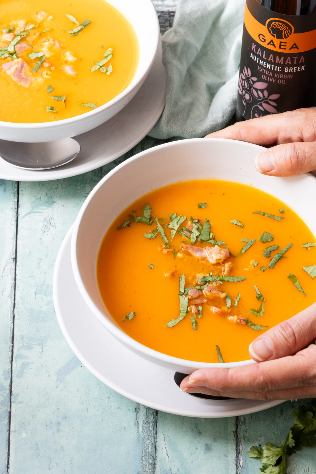 hands holding a bowl of butternut squash soup
