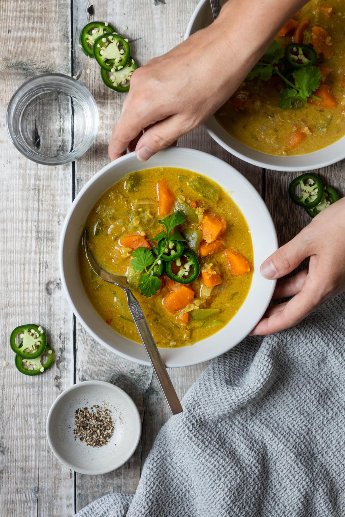 hands holding sweet potato lentil and tahini soup