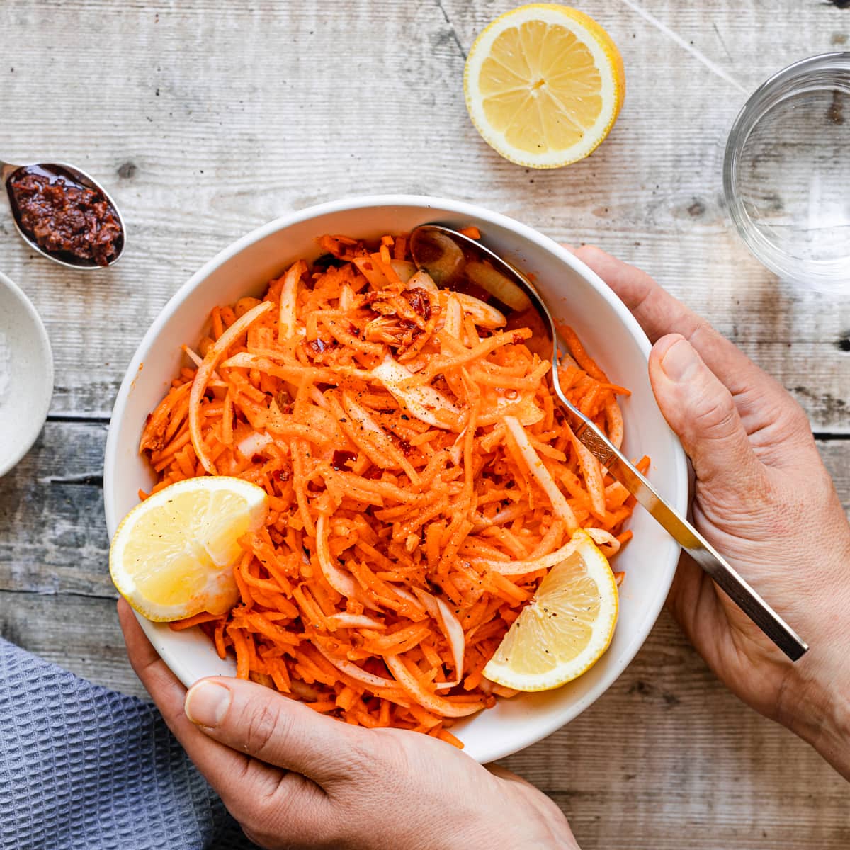 hands holding a bowl of harissa carrot salad