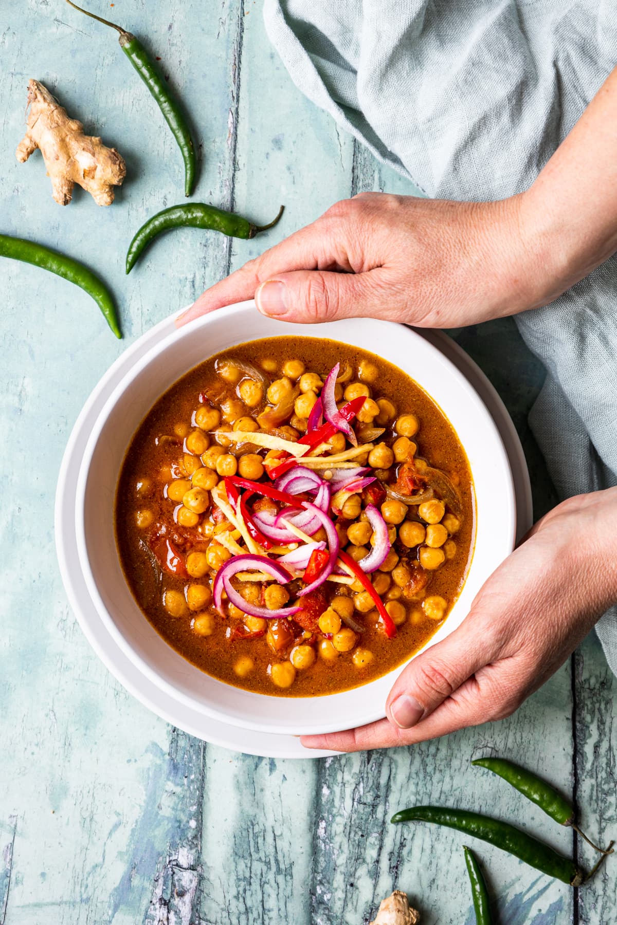 Hands holding a bowl of sour chickpea stew