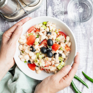 hands holding bowl of tuna cannellini bean salad