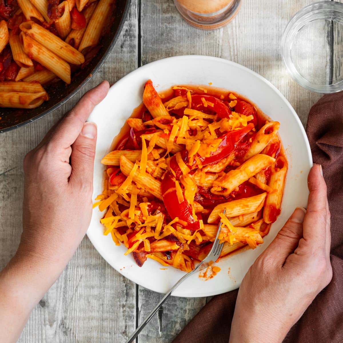 hands holding bowl of spicy tomato pasta