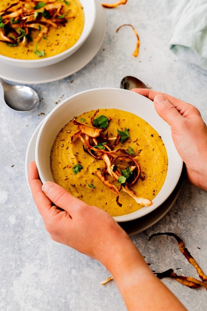 hands holding bowl of roasted parsnip soup