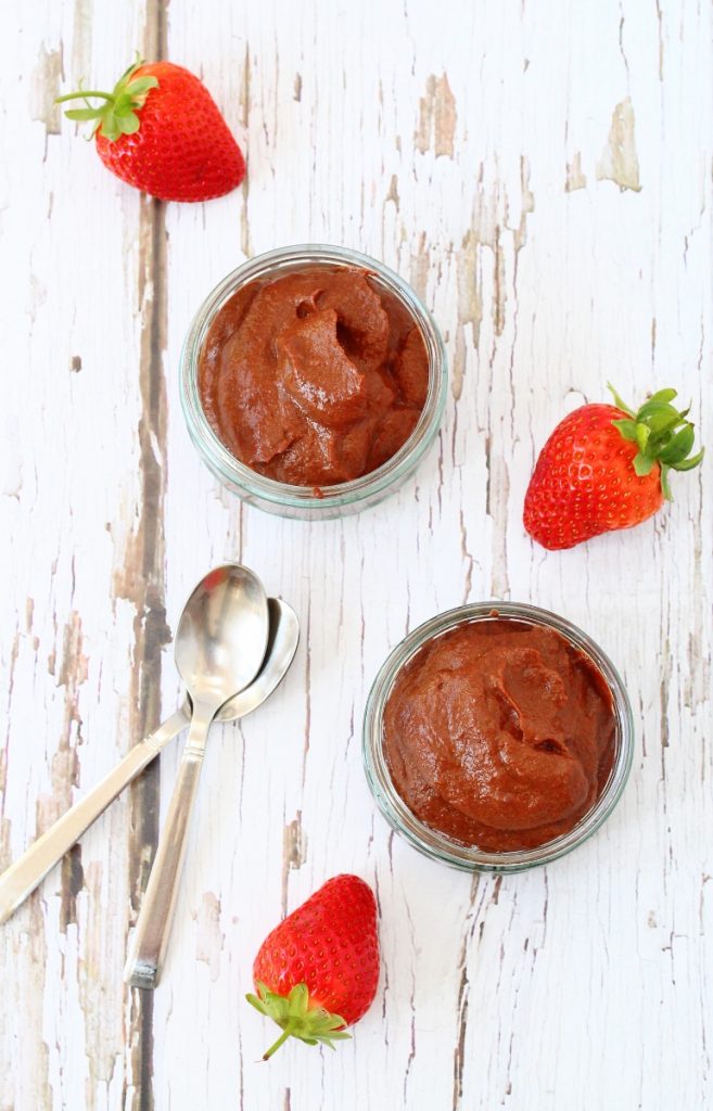 Two bowls of cauliflower chocolate mousse with strawberries and spoons