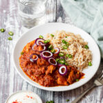 Red Goan chicken on a plate with rice