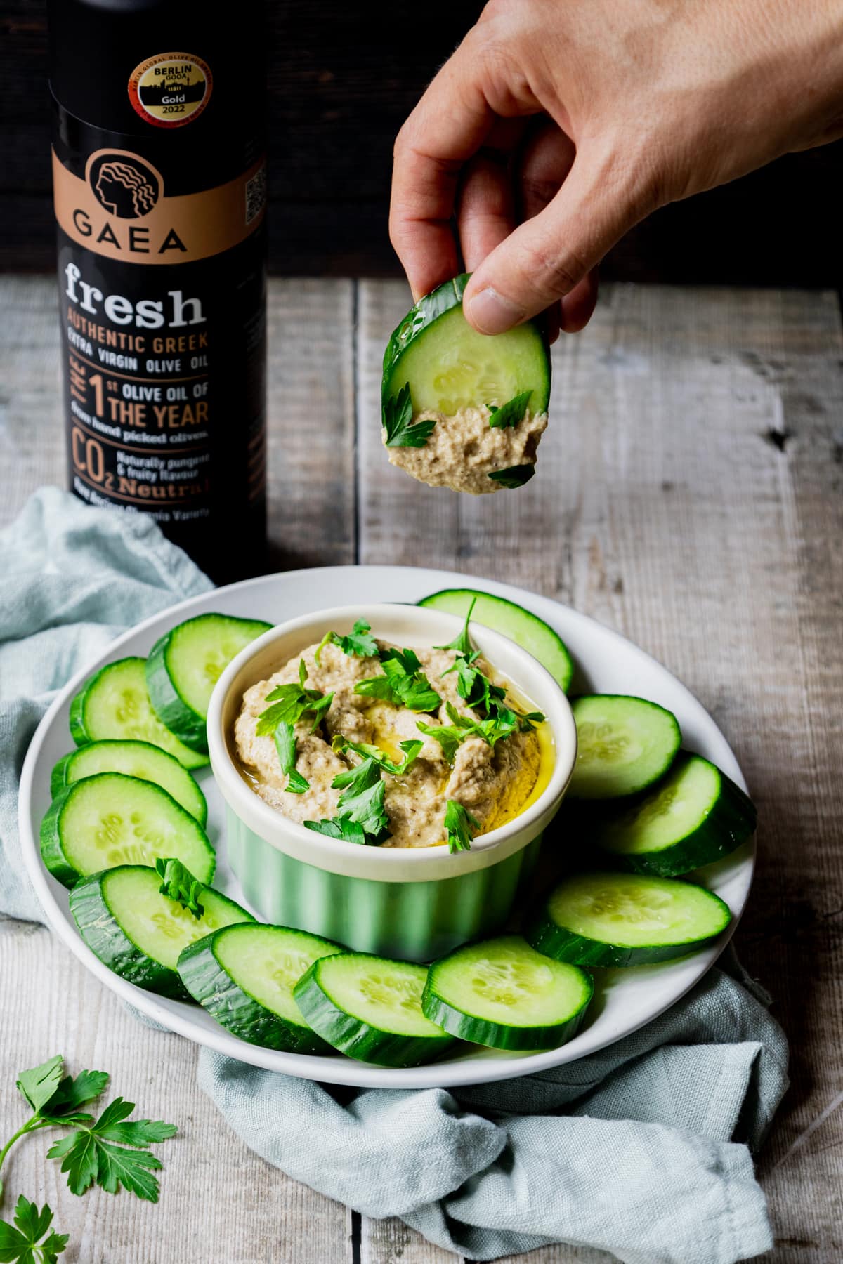 hand dipping cucumber into baba ghanoush