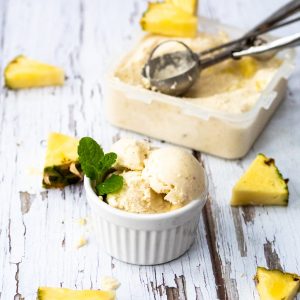 Bowl of pina colada nice cream and scoop plus pineapple pieces