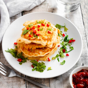 small stack of sweetcorn fritters topped with herbs