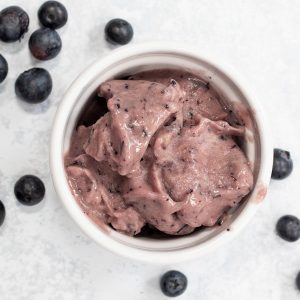 blueberry nice cream in a bowl with blueberries next to it