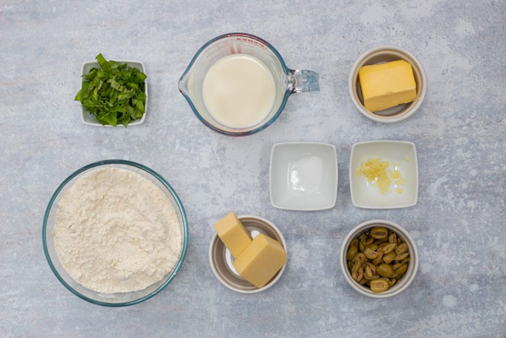 Ingredients for cheese and olive scones - self raising flour, butter, olives, mature cheddar cheese, butter, milk, garlic, salt, basil