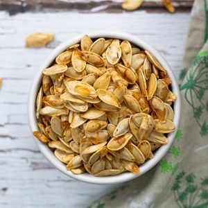 Bowl full of roasted pumpkin seeds seasoned with salt and pepper