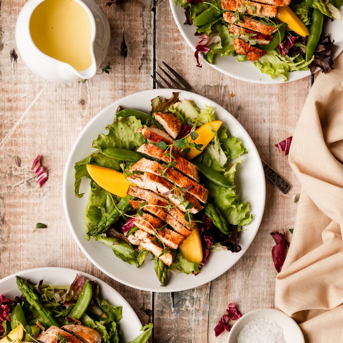 Plate of jerk chicken salad and jug of mango vinaigrette