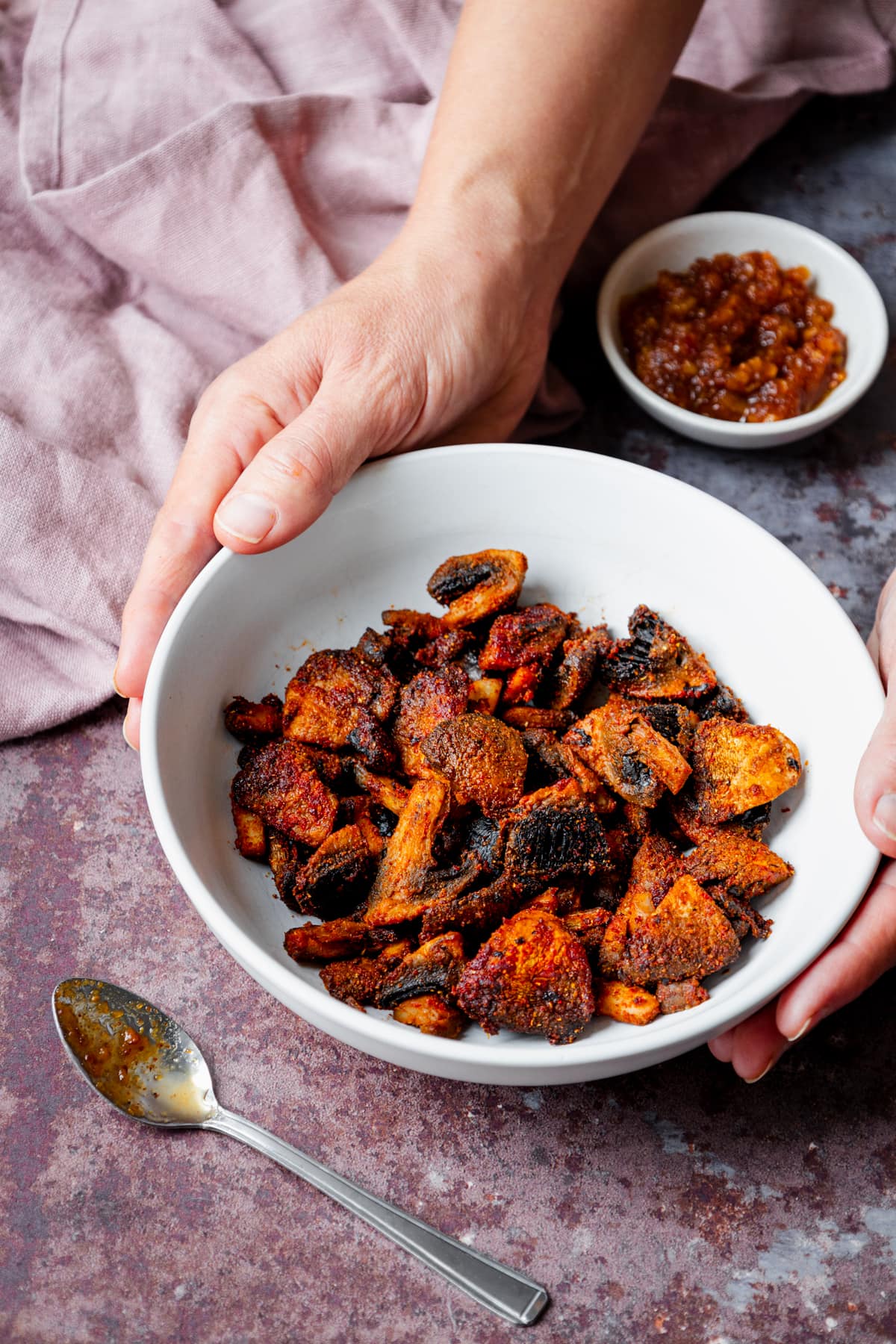 hands holding a bowl of spicy air fried mushrooms