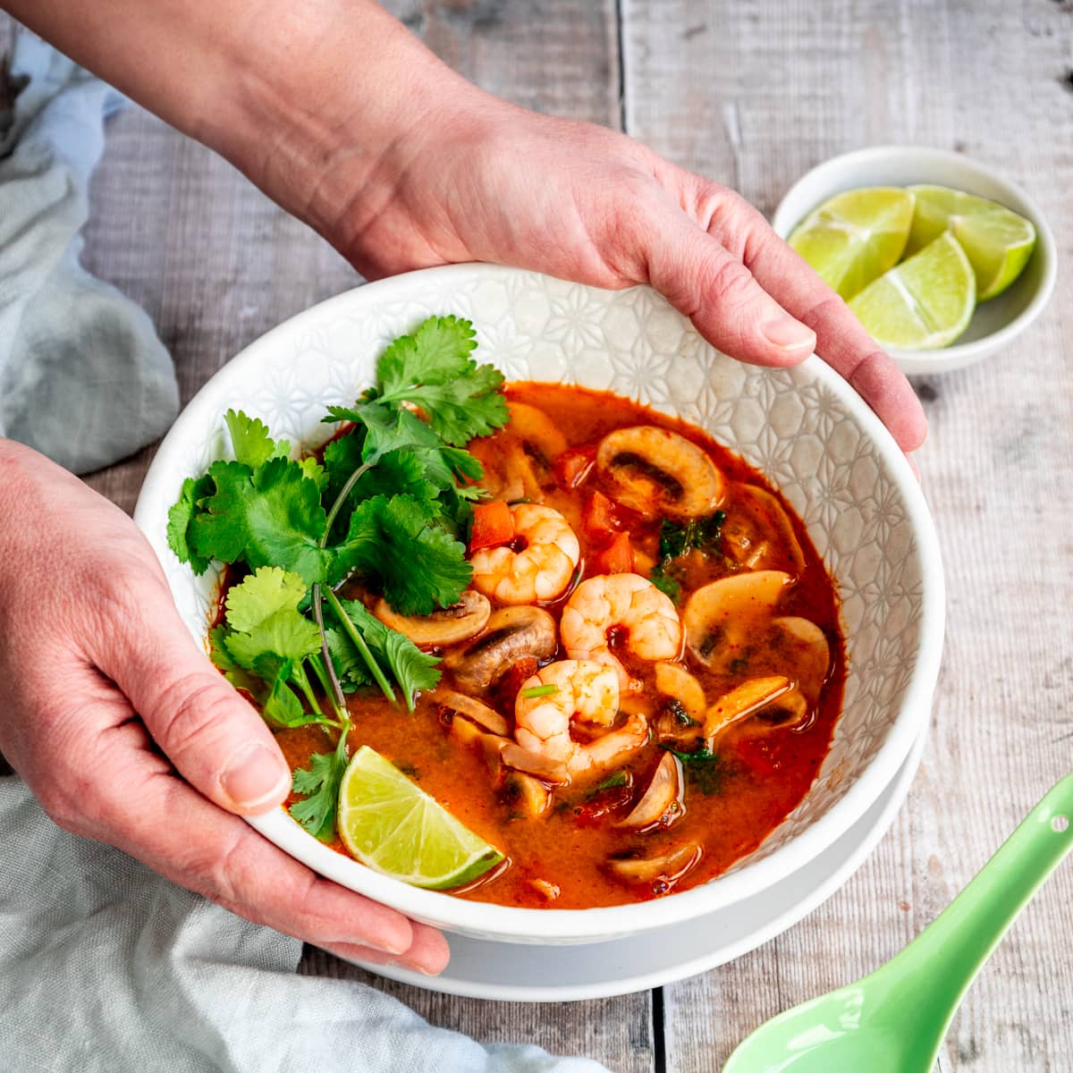 Hands holding bowl of tom yum soup